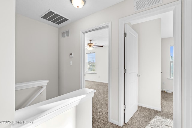 hallway featuring carpet floors, visible vents, and baseboards