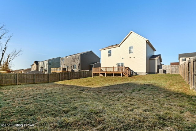 back of house with a fenced backyard, a lawn, and a wooden deck