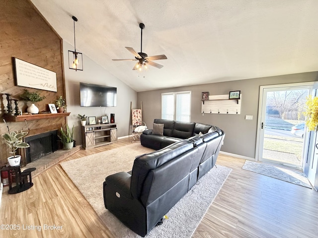 living room with lofted ceiling, a fireplace, light hardwood / wood-style floors, and a textured ceiling