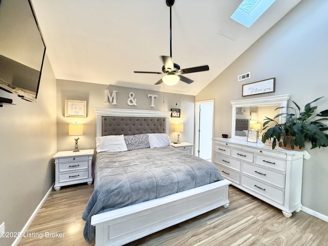 bedroom featuring vaulted ceiling with skylight, ceiling fan, and light hardwood / wood-style flooring