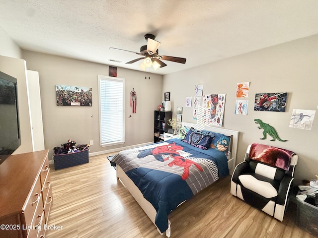 bedroom featuring ceiling fan, light hardwood / wood-style floors, and a textured ceiling