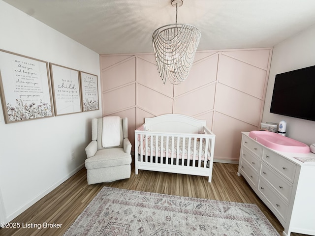 bedroom with hardwood / wood-style flooring, a crib, and a chandelier