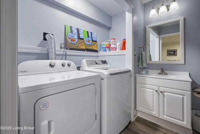 laundry room featuring dark wood-type flooring, cabinets, sink, and washing machine and dryer