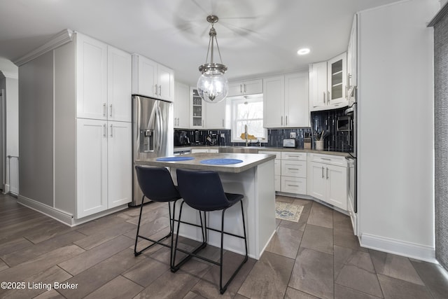 kitchen with a breakfast bar, appliances with stainless steel finishes, white cabinets, a kitchen island, and decorative light fixtures