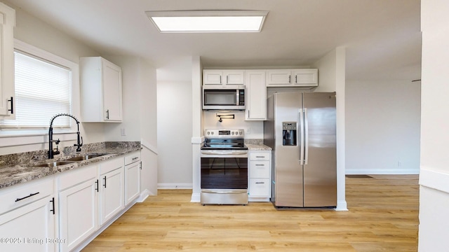 kitchen featuring light stone countertops, appliances with stainless steel finishes, sink, and white cabinets