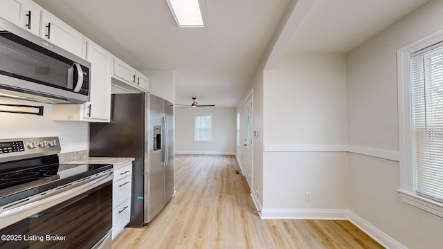 kitchen with stainless steel appliances, ceiling fan, white cabinets, and light wood-type flooring