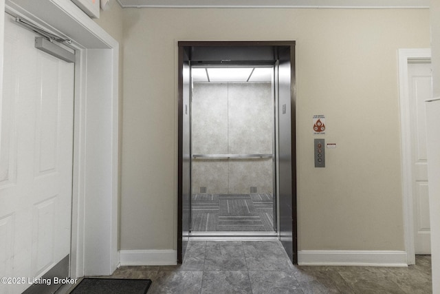 bathroom featuring elevator and baseboards