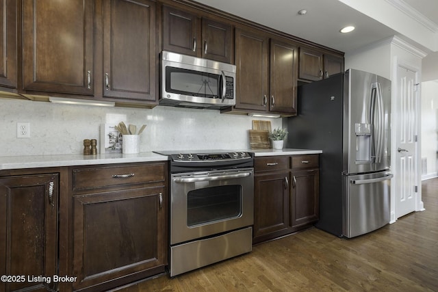 kitchen with stainless steel appliances, backsplash, dark brown cabinets, and dark wood-style floors