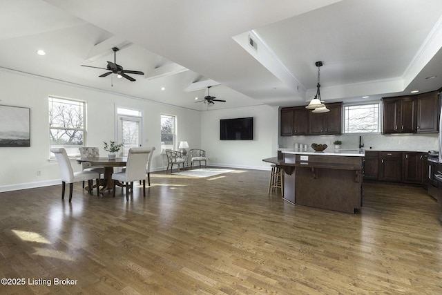 kitchen with visible vents, dark brown cabinets, a center island, dark wood-style floors, and a raised ceiling