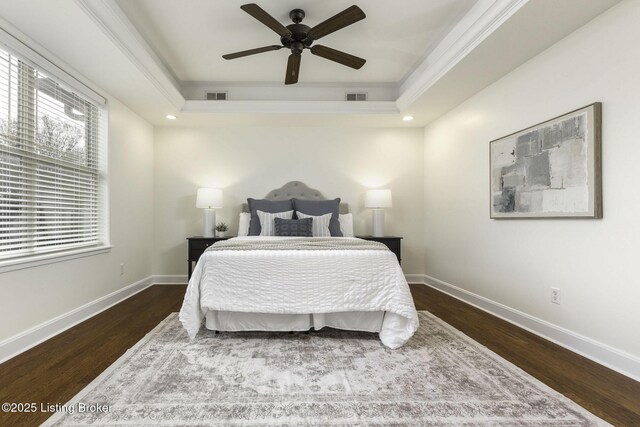 bedroom with visible vents, a raised ceiling, and wood finished floors