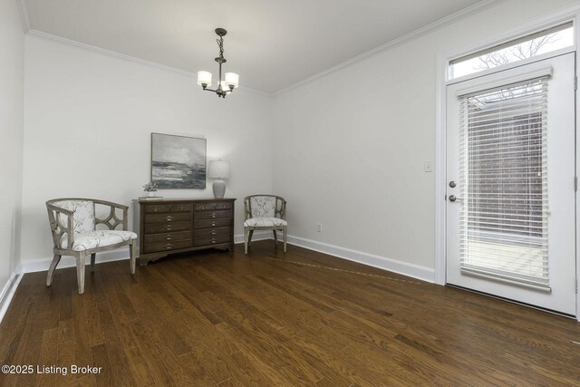 sitting room with a notable chandelier, baseboards, dark wood-type flooring, and crown molding