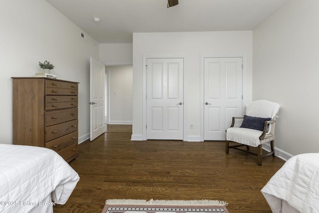 bedroom featuring multiple closets, baseboards, and wood finished floors