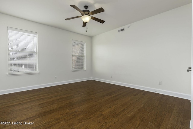 spare room with visible vents, baseboards, dark wood-style floors, and a ceiling fan