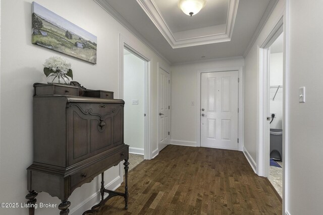 entrance foyer with ornamental molding, baseboards, a tray ceiling, and dark wood-style flooring