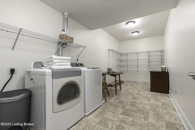 washroom featuring laundry area, washing machine and dryer, a garage, and baseboards