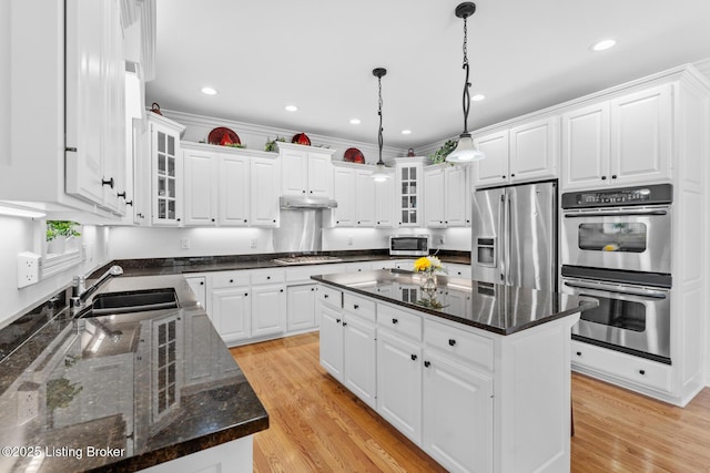 kitchen with a center island, stainless steel appliances, a sink, light wood-type flooring, and under cabinet range hood