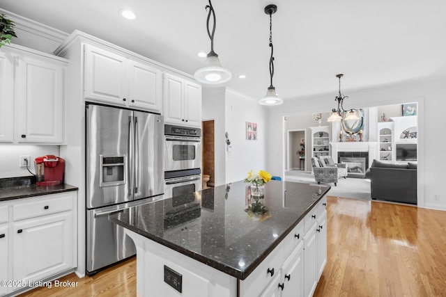 kitchen featuring appliances with stainless steel finishes, a glass covered fireplace, white cabinetry, and light wood-style floors