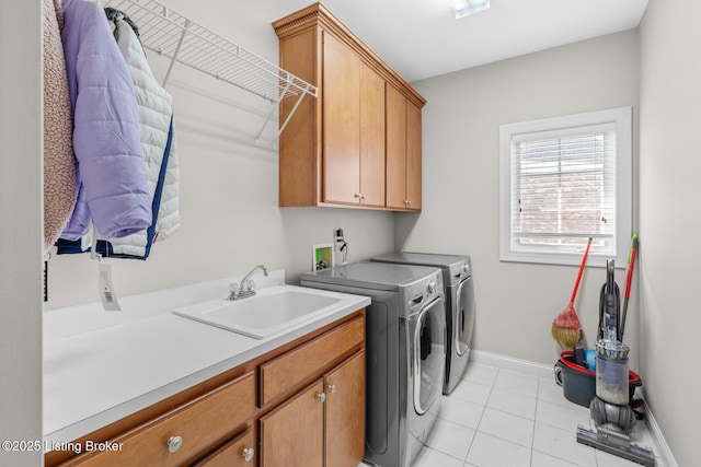 laundry area featuring cabinet space, light tile patterned floors, baseboards, separate washer and dryer, and a sink