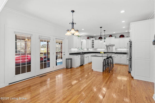 kitchen featuring appliances with stainless steel finishes, dark countertops, white cabinetry, and light wood-style floors