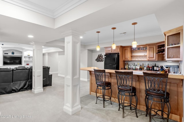 kitchen with crown molding, a breakfast bar area, open shelves, freestanding refrigerator, and ornate columns