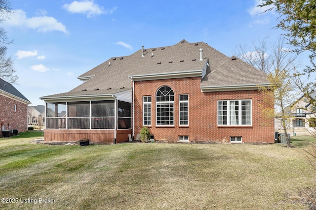 rear view of property featuring a yard, brick siding, roof with shingles, and a sunroom