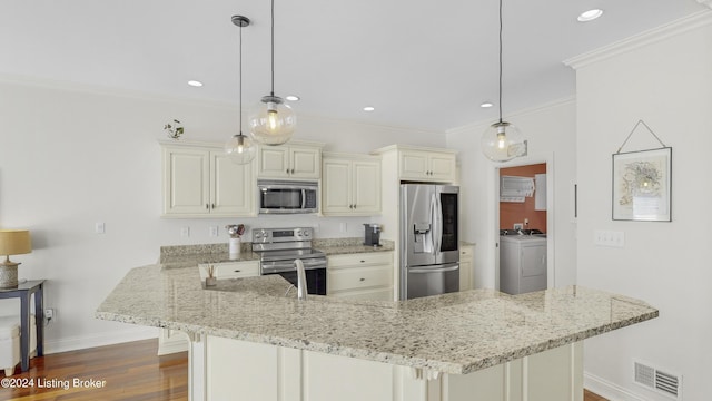 kitchen with washer and dryer, decorative light fixtures, stainless steel appliances, and cream cabinetry