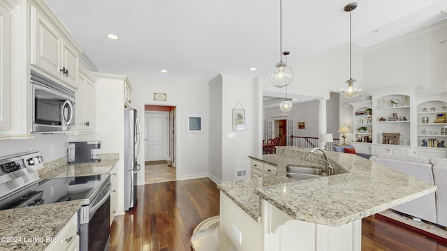 kitchen featuring appliances with stainless steel finishes, pendant lighting, sink, a breakfast bar area, and a spacious island