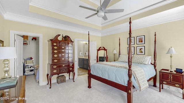 bedroom with crown molding, a spacious closet, light carpet, and a tray ceiling