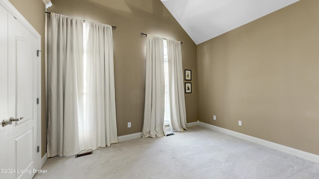 empty room featuring vaulted ceiling and light colored carpet