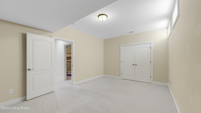 unfurnished bedroom with light carpet and a closet