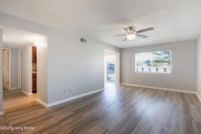 unfurnished room featuring dark wood-type flooring, ceiling fan, and a textured ceiling