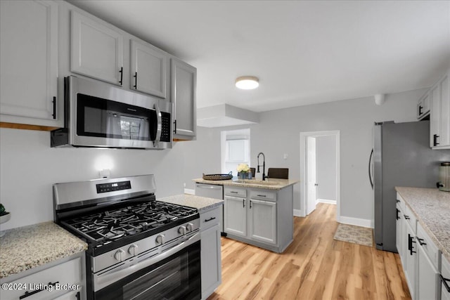 kitchen with stainless steel appliances, sink, gray cabinets, and light hardwood / wood-style flooring