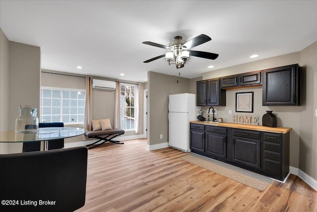 kitchen with sink, butcher block counters, white refrigerator, an AC wall unit, and light wood-type flooring