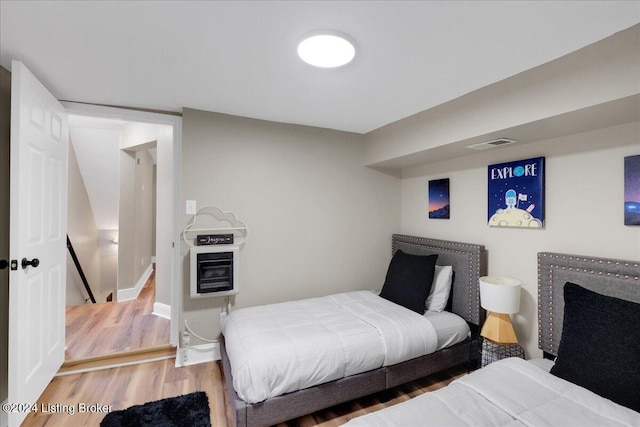 bedroom featuring hardwood / wood-style flooring and heating unit