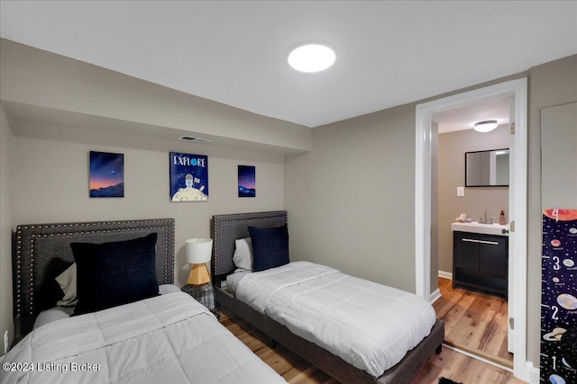 bedroom with sink, connected bathroom, and hardwood / wood-style floors