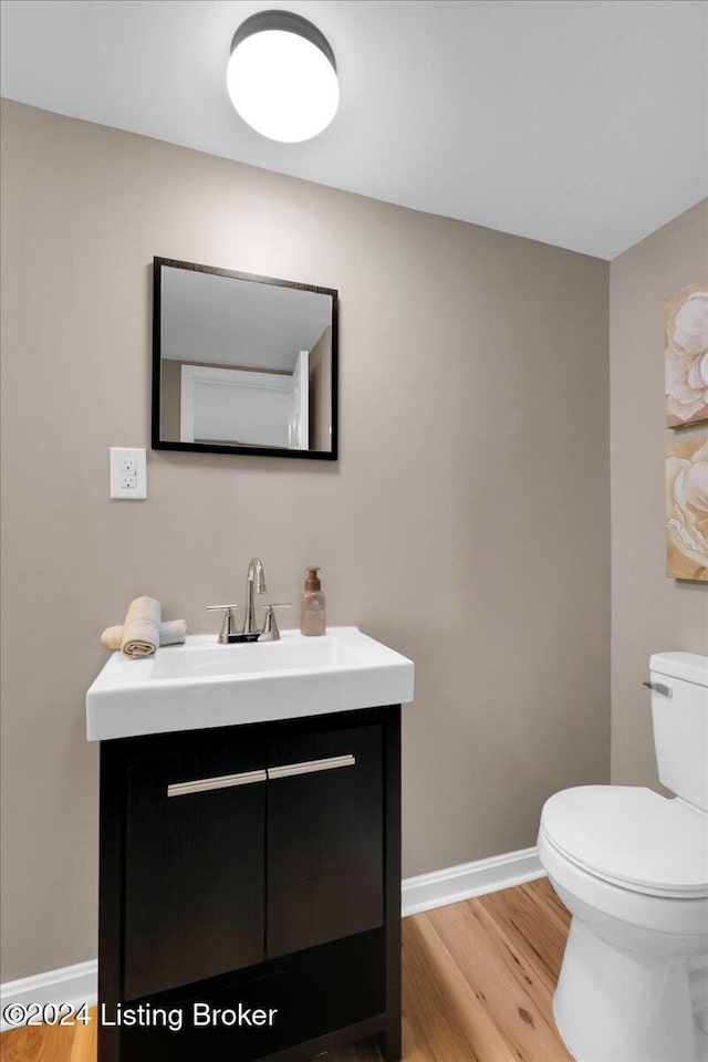 bathroom with vanity, toilet, and hardwood / wood-style floors