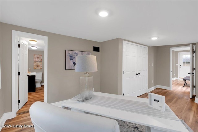 bedroom with ensuite bathroom, light wood-type flooring, and a closet