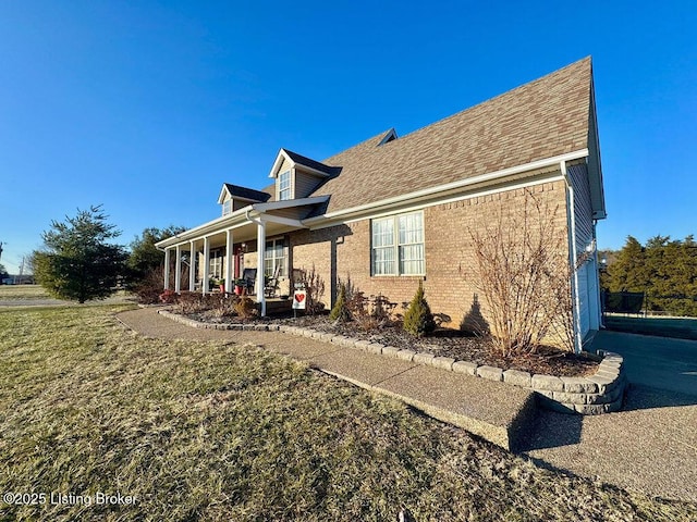 view of side of property with a porch and a lawn