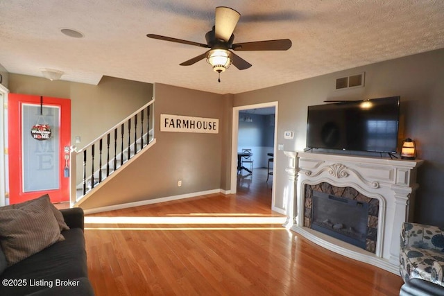 unfurnished living room featuring wood-type flooring, ceiling fan, and a textured ceiling