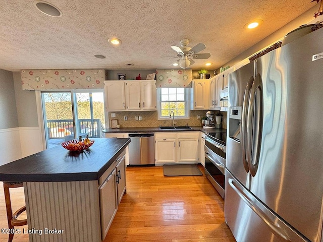 kitchen featuring sink, light hardwood / wood-style flooring, a breakfast bar area, appliances with stainless steel finishes, and white cabinetry