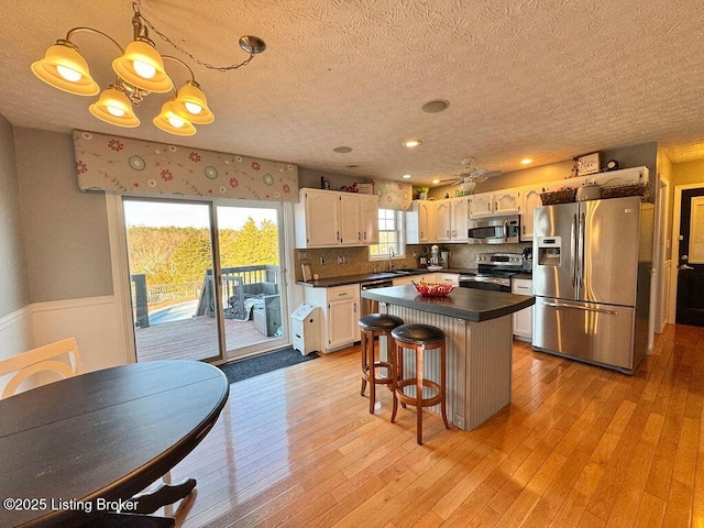 kitchen featuring pendant lighting, sink, white cabinetry, stainless steel appliances, and a kitchen bar