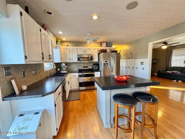 kitchen featuring white cabinetry, appliances with stainless steel finishes, sink, and a breakfast bar area