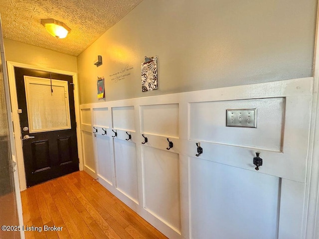 doorway to outside with a textured ceiling and light hardwood / wood-style flooring