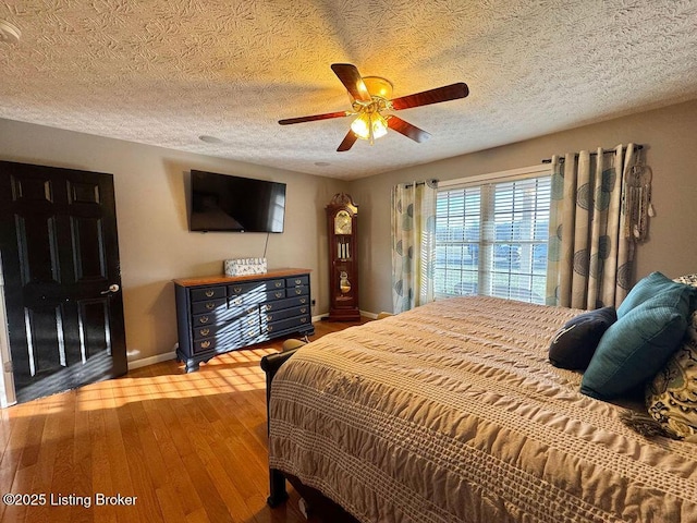 bedroom with ceiling fan, hardwood / wood-style floors, and a textured ceiling