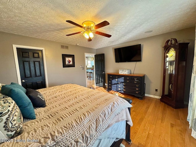 bedroom with a textured ceiling, light hardwood / wood-style flooring, and ceiling fan