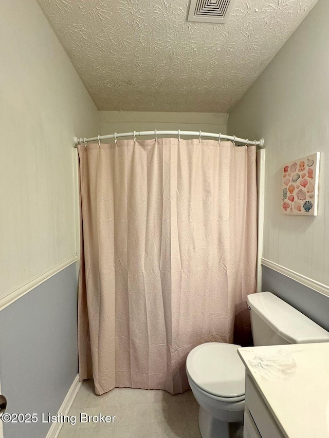 bathroom with vanity, a textured ceiling, curtained shower, and toilet