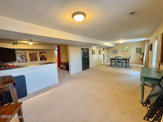 recreation room featuring light colored carpet and a textured ceiling