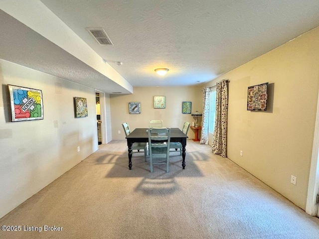 carpeted dining area with a textured ceiling