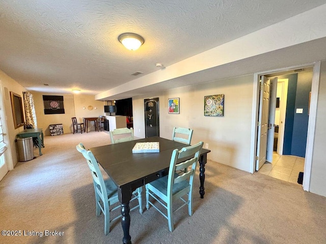 dining room with light colored carpet and a textured ceiling