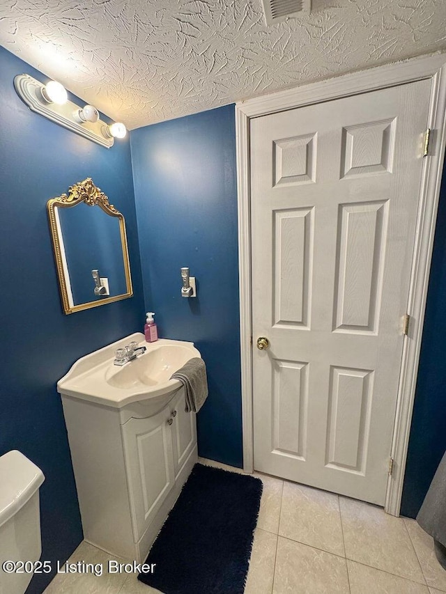 bathroom with vanity, a textured ceiling, tile patterned floors, and toilet